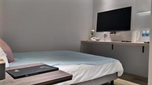 a bedroom with a bed with a television on a shelf at 蘆思特六合民宿 in Kaohsiung