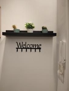 a welcome sign on a wall with potted plants on it at Apartamento La Carola in Bilbao