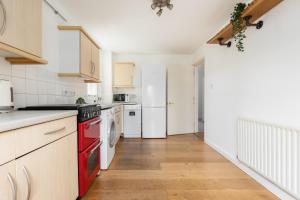 a kitchen with white cabinets and a red oven at The Clapham Terraced House in London