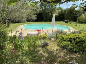 una piscina con sombrilla en un jardín en Gîte Corsi Gallega, en Sauzet