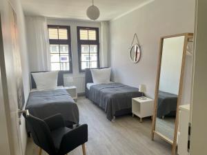 a bedroom with two beds and a mirror and a chair at discovAIR - Eisenach Karl14 - Vollausgestattete Apartments mit Netflix in der Fussgängerzone in Eisenach