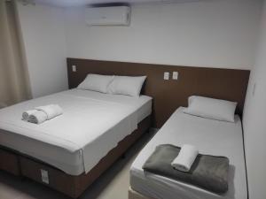 duas camas num pequeno quarto com lençóis brancos em Apartamento Central em Ametista do Sul