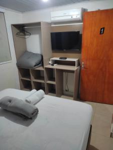 Cette chambre comprend deux lits, un bureau et une télévision. dans l'établissement Apartamento Central, à Ametista do Sul