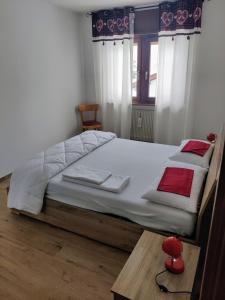 a bedroom with a bed with white sheets and red pillows at Falcade Dolomiti La Quiete piano terra in Fregona