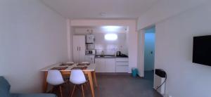 a kitchen with white cabinets and a table and stools at Departamento en Mendoza in Mendoza