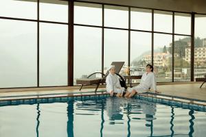 two women in white robes sitting next to a swimming pool at Amazing Hotel Sapa in Sapa