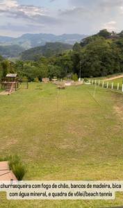 a large field of grass with trees and mountains in the background at Refúgio nascer das águas in Gravatal