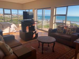 a living room with a couch and a television and the ocean at Marine 5 Boutique Hotel in Gansbaai
