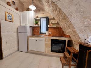 cocina con nevera blanca y pared de piedra en A casa di Tullio en Fasano