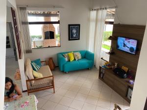 una sala de estar con un sofá azul y una niña pequeña en Casa 08 Quadra 06 Cond. Viva Vida, en Aracaju