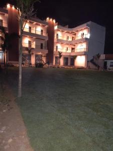 een groot appartementencomplex 's nachts met een gazon voor de deur bij AKS INTERNATIONAL HOTEL AND RESORT in Sasarām