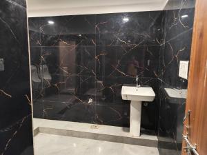 uma casa de banho com um lavatório e uma parede em mármore preto em AKS INTERNATIONAL HOTEL AND RESORT em Sasarām
