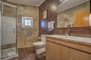 a bathroom with a toilet and a sink and a shower at Fika Guest House in Nazaré