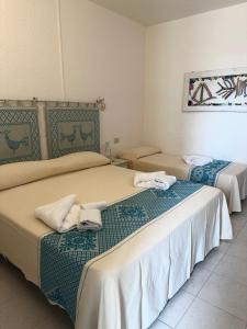 サンタ・テレーザ・ガッルーラにあるHotel Canne al Ventoのホテルルーム内のベッド2台(タオル付)