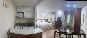 Flat no Itaim Bibi في ساو باولو: مطبخ وغرفة نوم مع سرير وطاولة