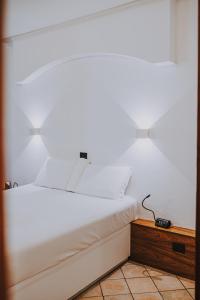 Una cama blanca con dos luces encima. en Albergo Delle Regioni, Barberini - Fontana di Trevi en Roma