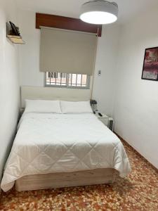 1 dormitorio con 1 cama blanca y ventana en Apartamento San Agustín - Alojamientos El Duque, en Córdoba