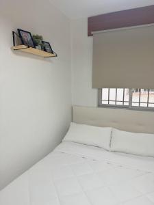 Cama blanca en habitación con ventana en Apartamento San Agustín - Alojamientos El Duque, en Córdoba
