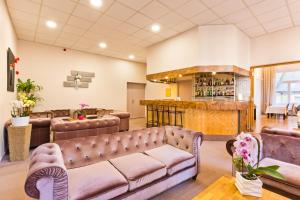 a waiting room with leather couches and a bar at Hôtel du Parc in Le Mont-Dore