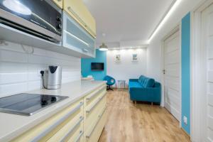 a kitchen with white cabinets and a blue couch at Apartament Sopocki in Sopot