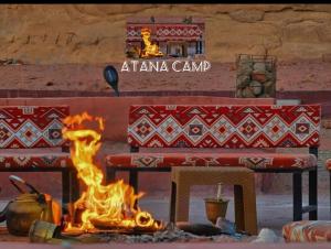 a fire burns in front of a table with a table at RUM ATANA lUXURY CAMP in Wadi Rum