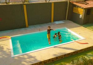 un hombre y dos niños en una piscina en Suíte Luxo Contêiner en Boa Vista