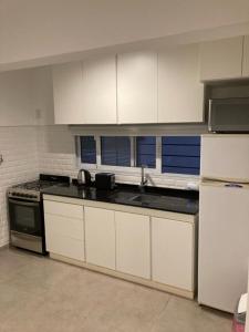 a kitchen with white cabinets and a black counter top at Casa en General Rodríguez. in General Rodríguez