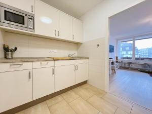 a kitchen with white cabinets and a large window at Ferienwohnung Westerland strandnah Balkon Strandläufer 1 & 2 in Westerland