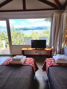 a room with two beds and a desk and a window at Punta Negra in Villa Pehuenia