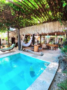 a swimming pool in a resort with a thatched roof at Coco-Knots Kite - Ilha do Guajiru in Itarema