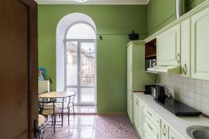 a kitchen with green walls and a table and chairs at Soborniy Hostel in Lviv