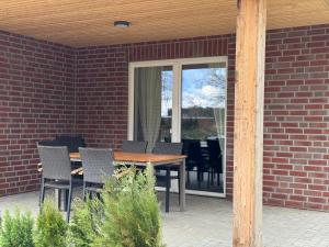 a patio with a table and chairs on a brick wall at Ferienhaus Wintermoor Ganzer Bungalow in Schneverdingen