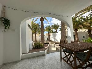 un patio al aire libre con una mesa de madera y palmeras en Santa Úrsula 21 en Costa Calma