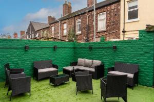 a patio with chairs and a green wall at Home @ Arkles Lane in Liverpool