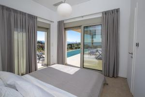 a bedroom with a bed and a balcony with a view at ELYANE VILLAS near AMMOUSSA BEACH in Évyiros