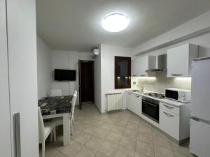a kitchen with white appliances and a table with a table at Ciclamino Appartamento Roma in Infernetto