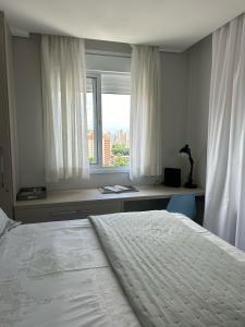 a bedroom with a white bed and a window at Novo, lazer completo e 3 quadras da Av. Paulista. in São Paulo