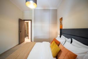 a bedroom with a bed with white sheets and orange pillows at Central 2 Bdrm Aprt In Koukaki! in Athens
