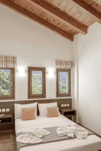 1 dormitorio con 2 camas y 2 ventanas en Villa Irini, en Koxaré