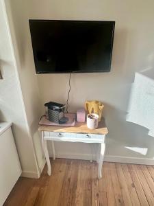 a small white table with a television on a wall at La Douceur - 4 personnes - BCLA in Le Mans