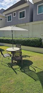 a table and two chairs with an umbrella on the grass at Option Full Service Residence in Rio de Janeiro