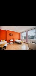 a living room with orange walls and a couch at Neasdon's Guest Nest- 7 mins drive to Wembley Stadium in London