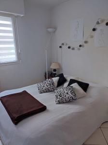 - un lit blanc avec des oreillers dans la chambre dans l'établissement Maison Guidel Plages 4 à 8 personnes, à Guidel
