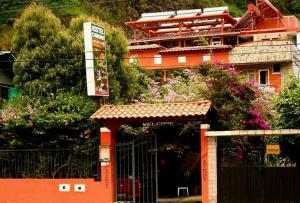 an orange building with a gate in front of it at Hostal Chimenea in Baños