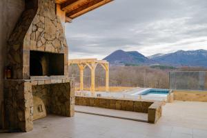 eine Terrasse mit einem Steinkamin und einem Pool in der Unterkunft Къщата на Mечтите / House of the Dreams in Aprilzi