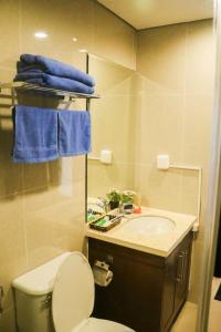 een badkamer met een toilet, een wastafel en blauwe handdoeken bij Vinhomes Royal City#3BR Serviced Apartment in Hanoi