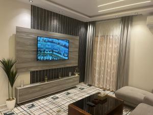 a living room with a television on a wall at Nourth House ApartHotel in Al Qurayyat