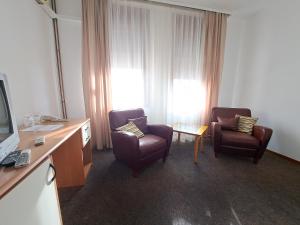 Pokój hotelowy z 2 krzesłami i telewizorem w obiekcie Hotel Marica w Niszu