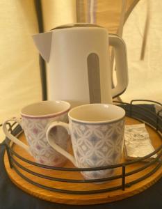 The Getaway - Seascape Belle Tent - Couples Luxury Glamping Belle Tent في دونغارفان: كوبين على صحن مع وعاء الشاي عليه