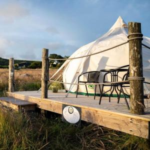 un banc sur une promenade avec une tente dans l'établissement Seascape Belle Tent - 2 Person Luxury Glamping Belle Tent, à Dungarvan